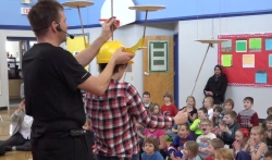Paul Isaak helps a student balance 5 spinning plates
